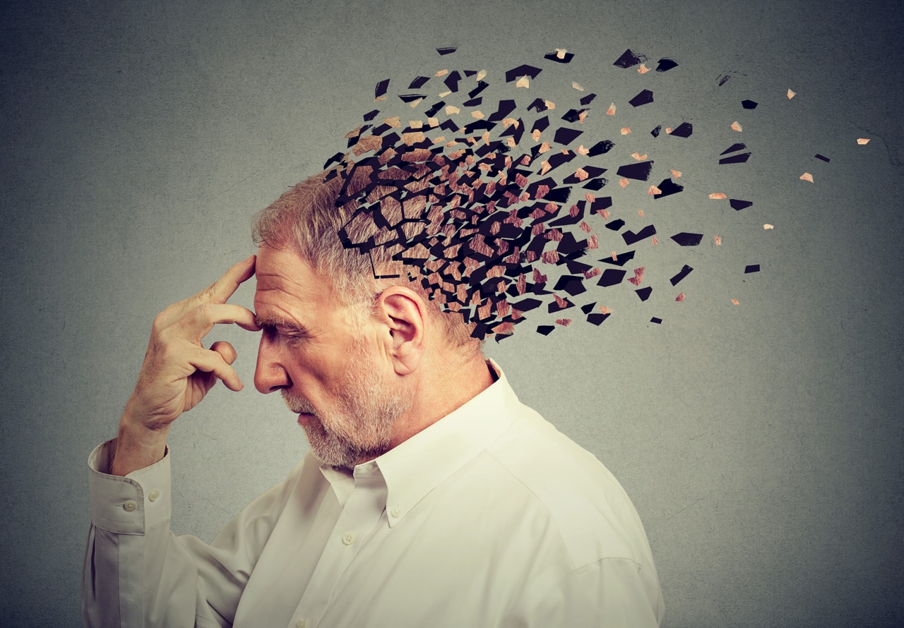 Ein älterer Mann hält sich die Hand an die Stirn, sein Kopf löst sich auf als Symbol für Alzheimer Demenz